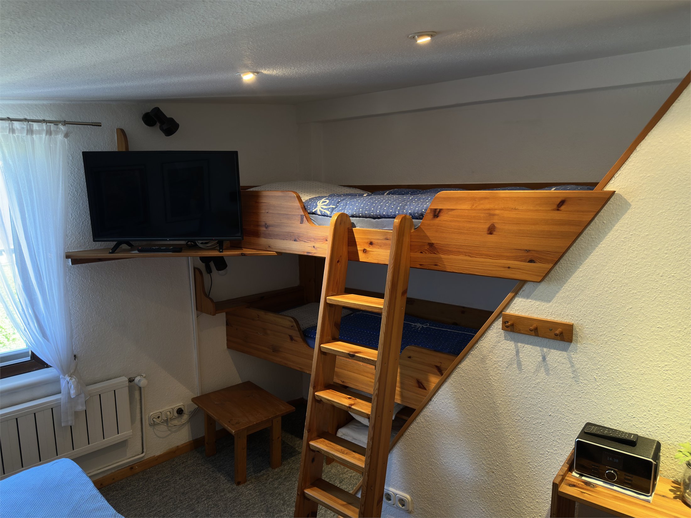 Holzkojen mit Leiter und Fernseher im Schlafbereich