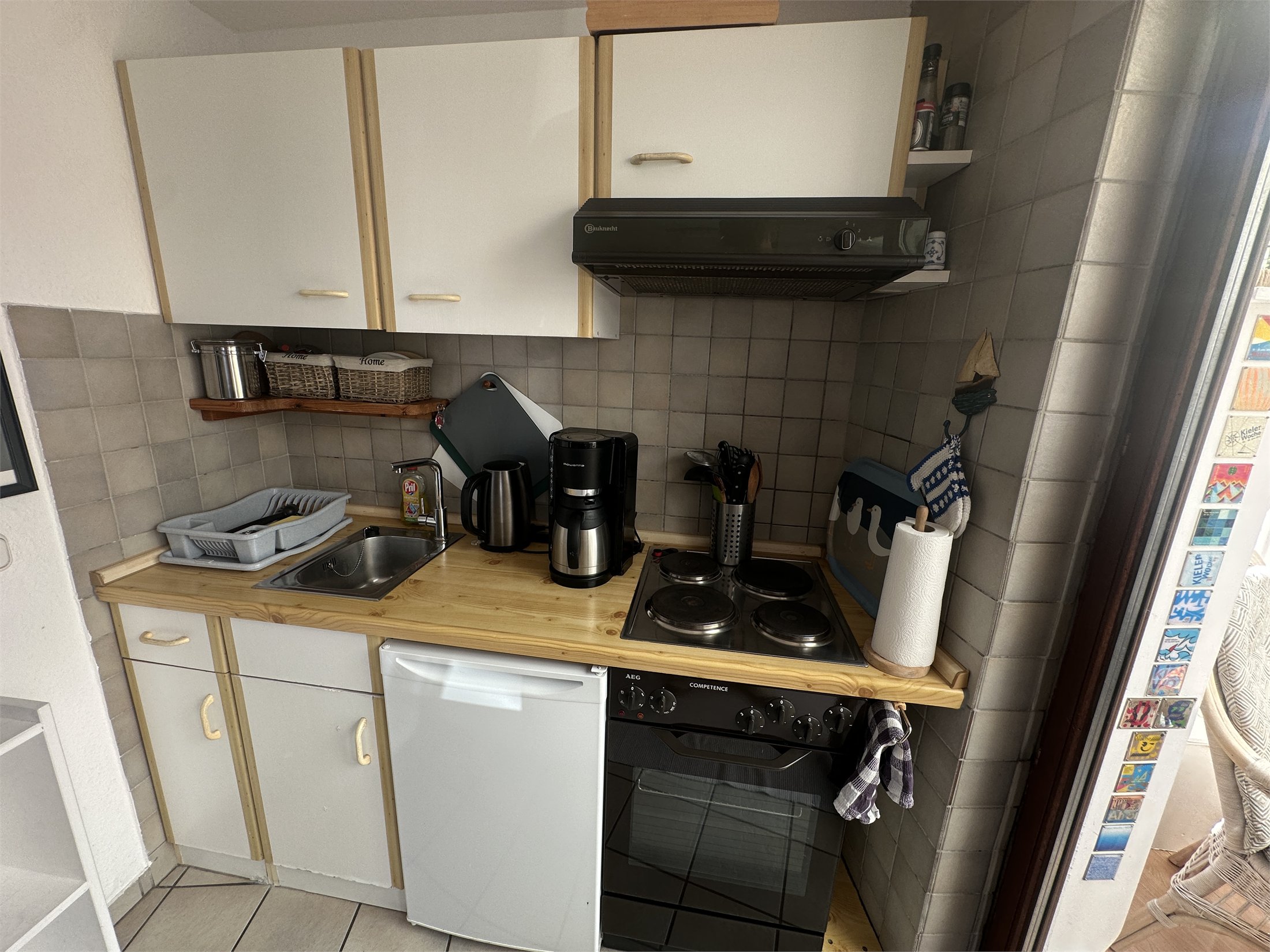 Kompakte Küche mit Backofen, Kochfeld, Kühlschrank und Kaffeemaschine