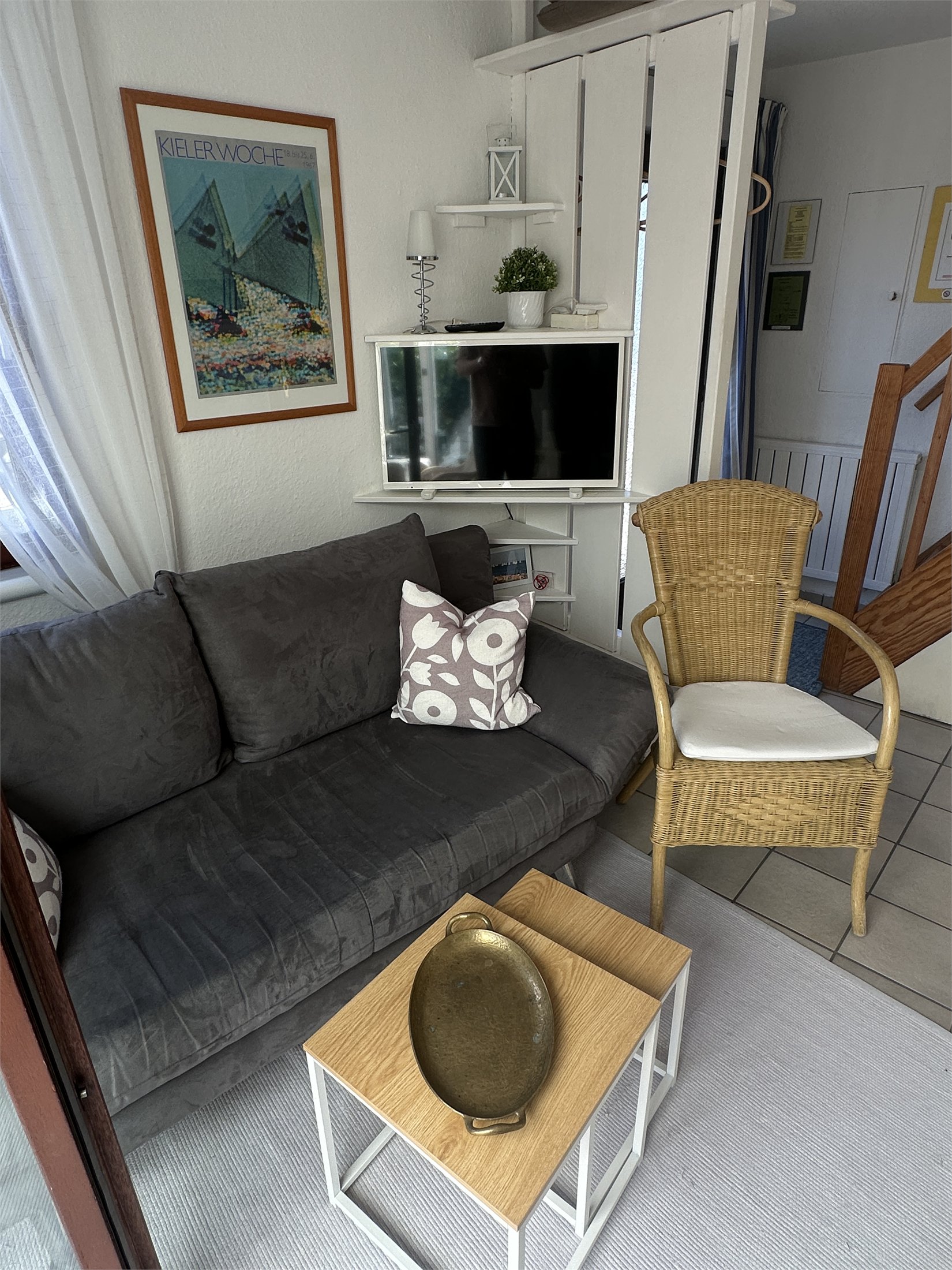 Wohnbereich mit Sofa, Fernseher, Sessel und Treppe